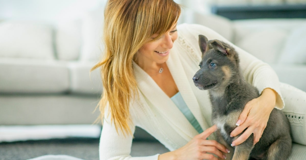 First-time dog owner in Oklahoma City bonding with a young puppy indoors.