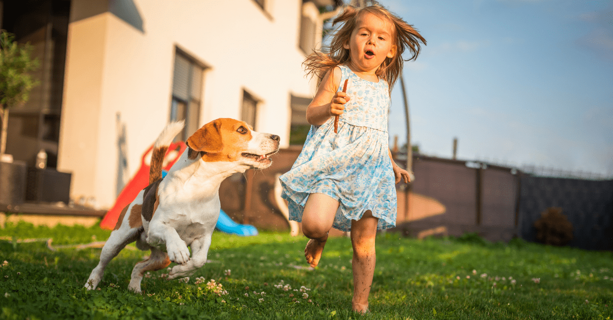 Little girl playing with her dog in a clean backyard after weekly pet waste removal service in Oklahoma City.