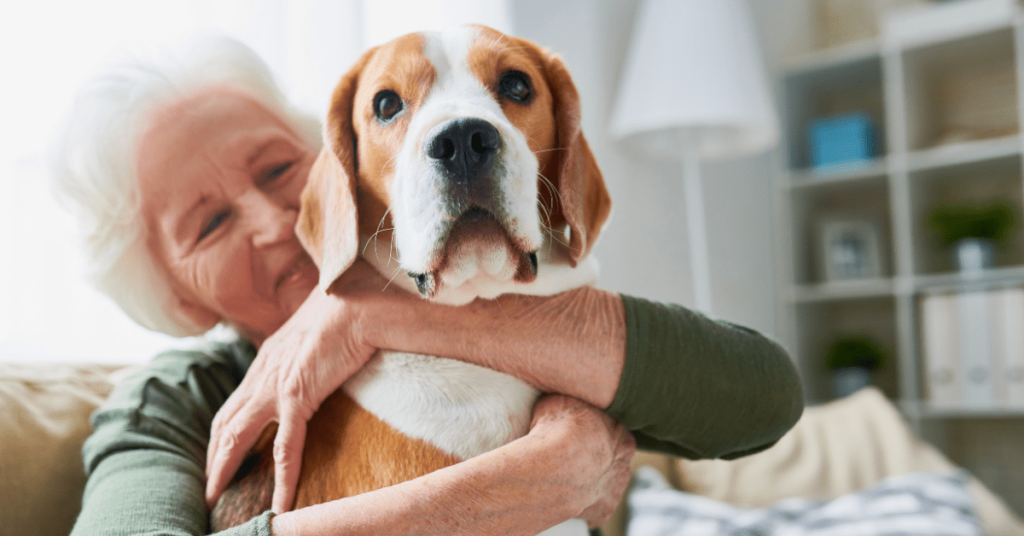 Senior pet owner smiling and hugging her dog at home after receiving a thoughtful poop scoop service gift in Oklahoma City.