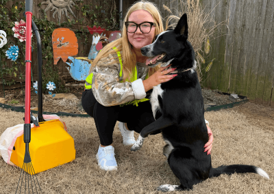 Poop Free OKC scoop technician bonding with a dog during professional pet waste removal service in a residential yard in Yukon, Oklahoma.